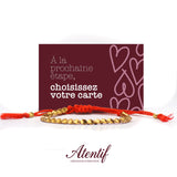 Bracelet Atentif avec perles dorées martelées et cordon tressé rouge.
