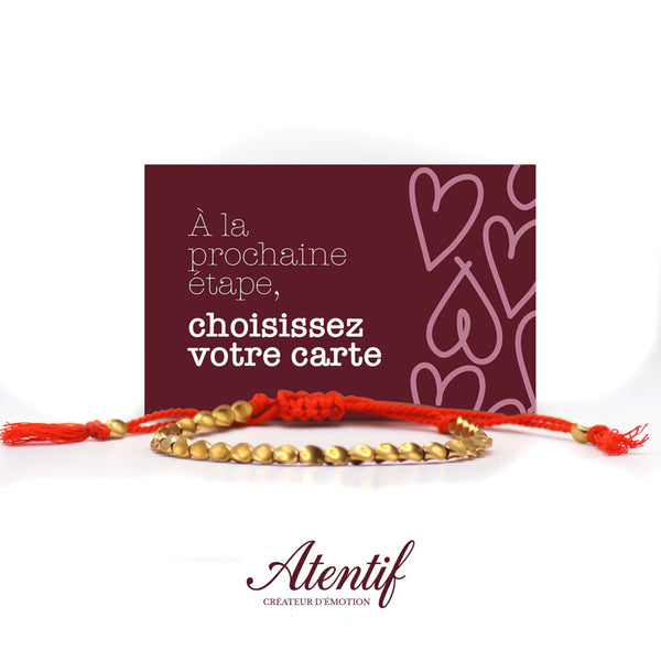 Bracelet Atentif avec perles dorées martelées et cordon tressé rouge.
